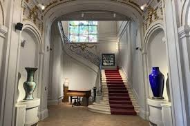 A grand staircase with a red carpet between two large vases